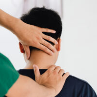 Physical therapist treating a client's neck, addressing headache symptoms